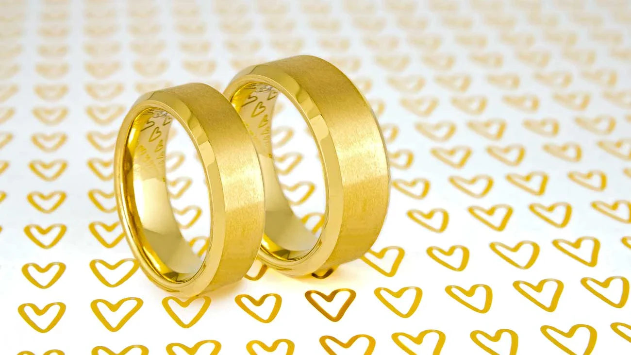 A minimal assortment of wedding bands for men and women displayed vertically on a slightly reflective white surface.