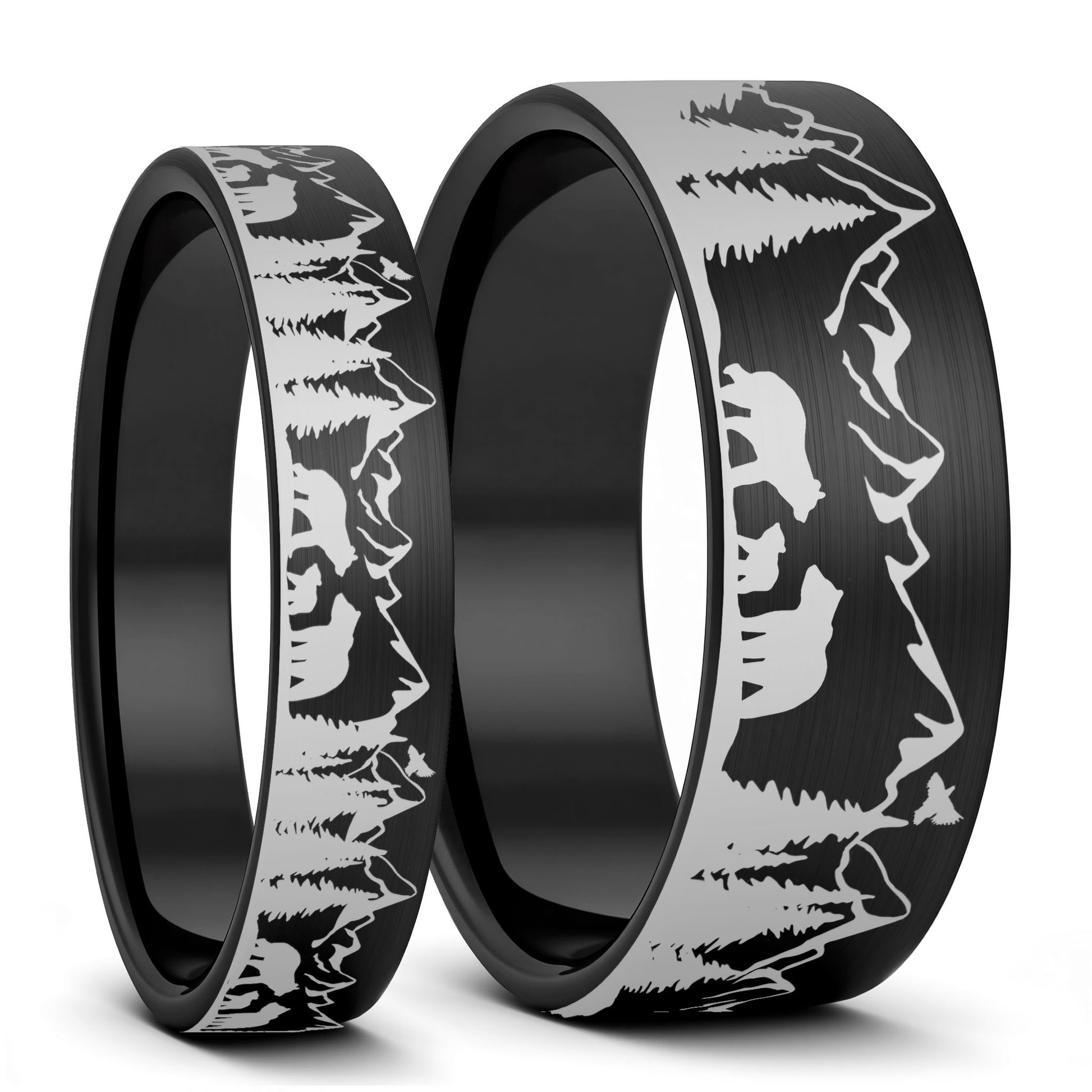 Two black rings with mountain and bear engraving on a white background
