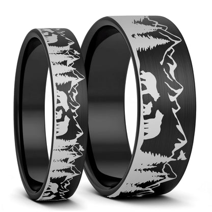 Two black rings with mountain and bear engraving on a white background