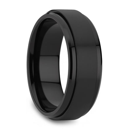 A black metallic band ring with a beveled edge and a smooth, polished finish, shown at an angle on a white background.