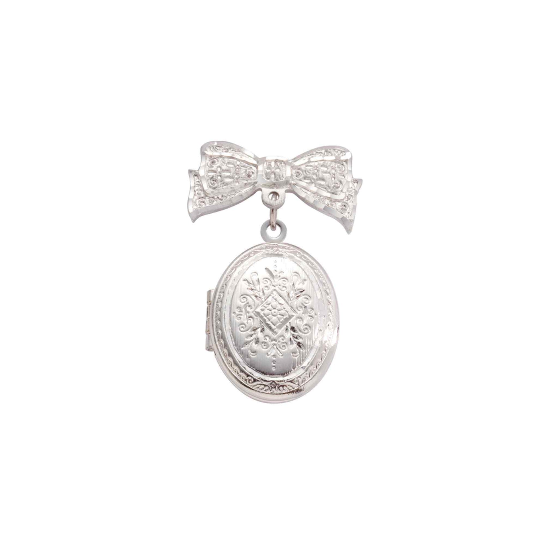 A bow pin and oval locket with bezel inserts displayed on a neutral white background.