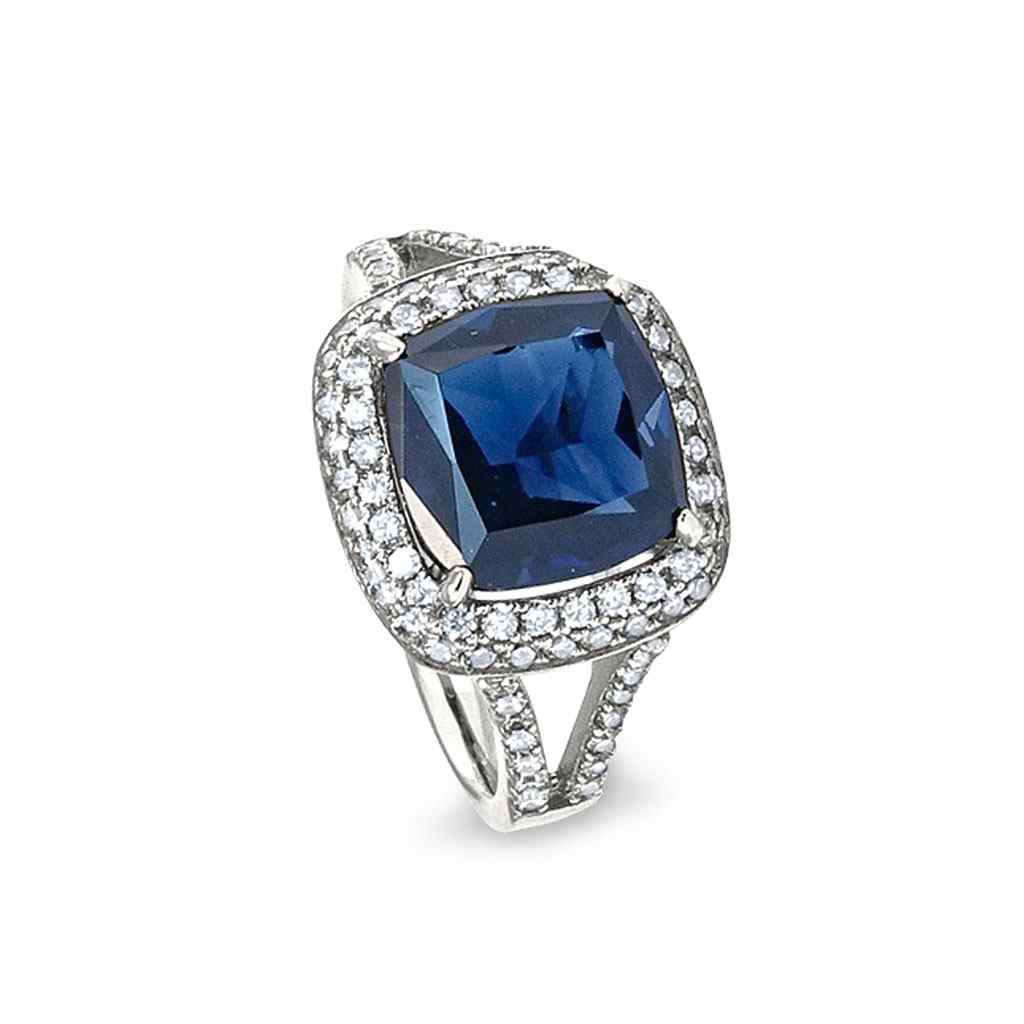 A emerald cut ring with synthetic blue sapphire and simulated diamonds displayed on a neutral white background.