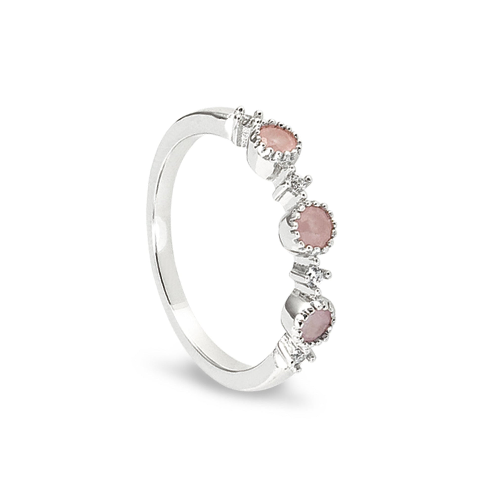A pink three stone ring with simulated diamonds displayed on a neutral white background.
