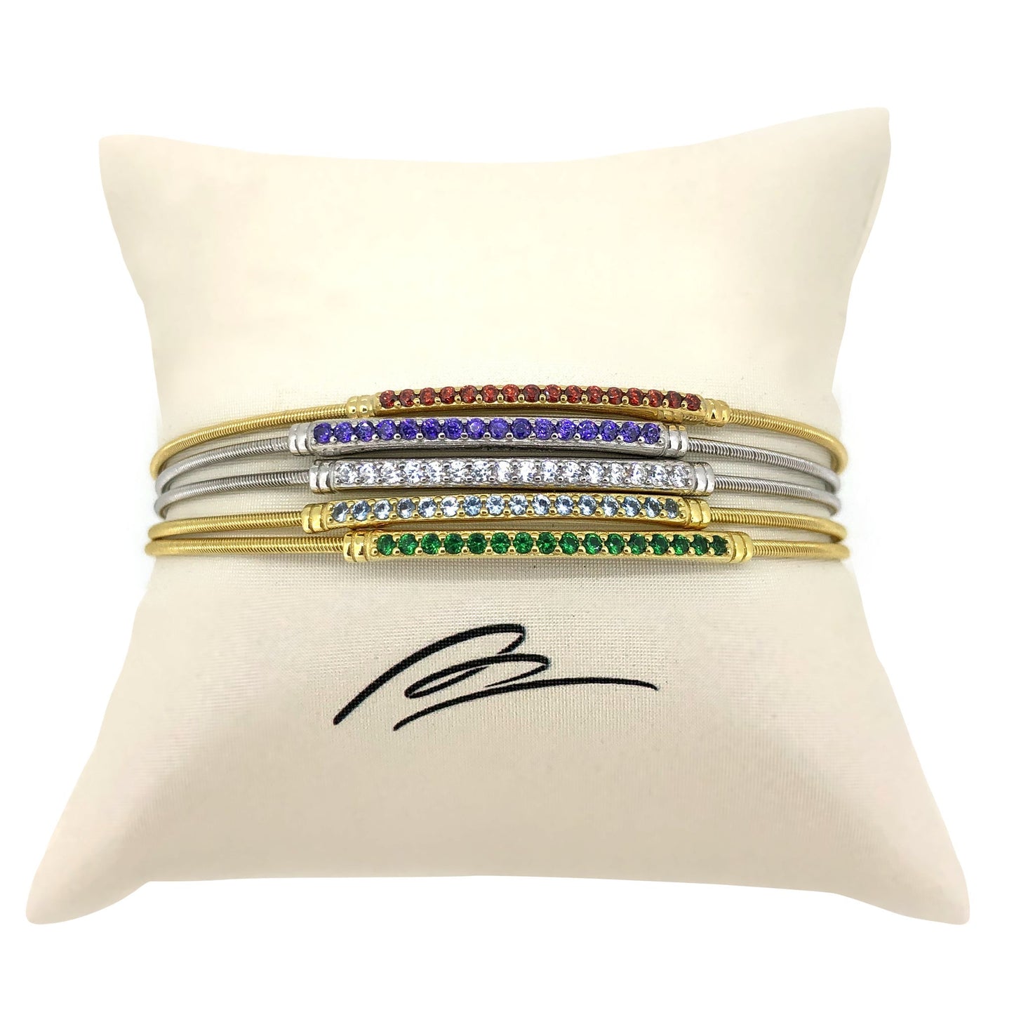 A rainbow gemstone stack of flexible cable bracelets displayed on a neutral white background.